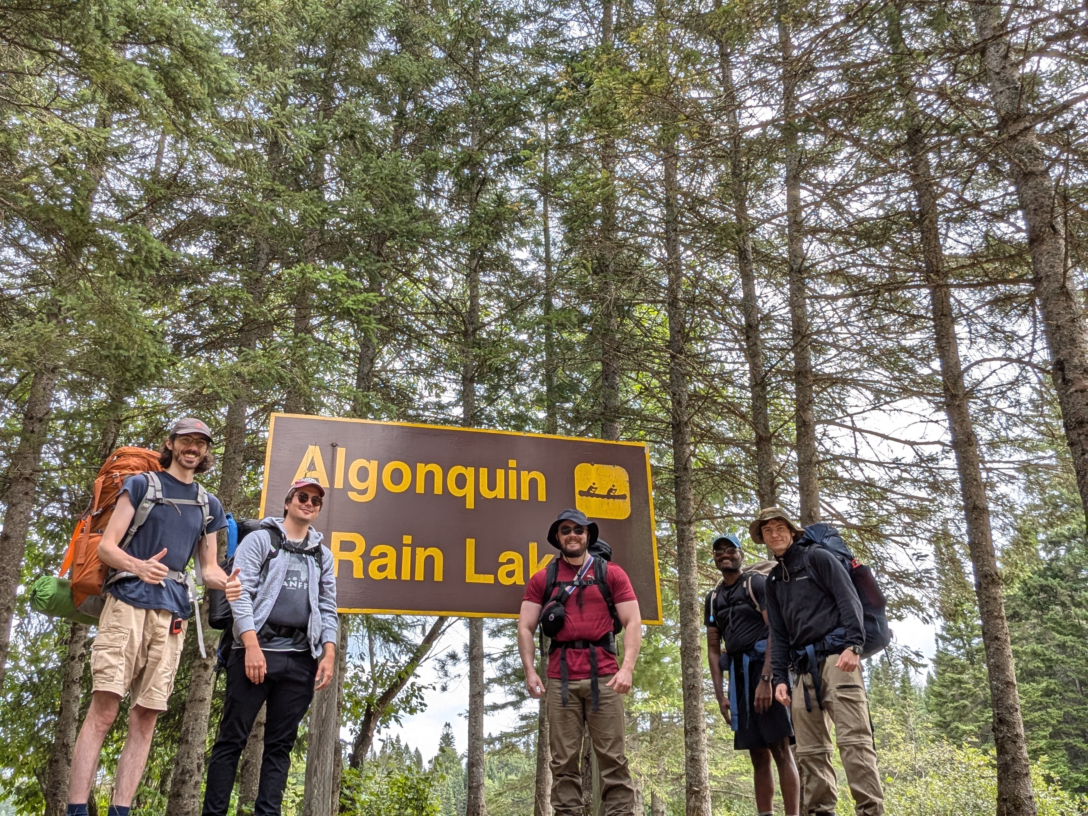 Group of 5 guys in front of a sign that says Algonquin Rain Lake at the start of the hike