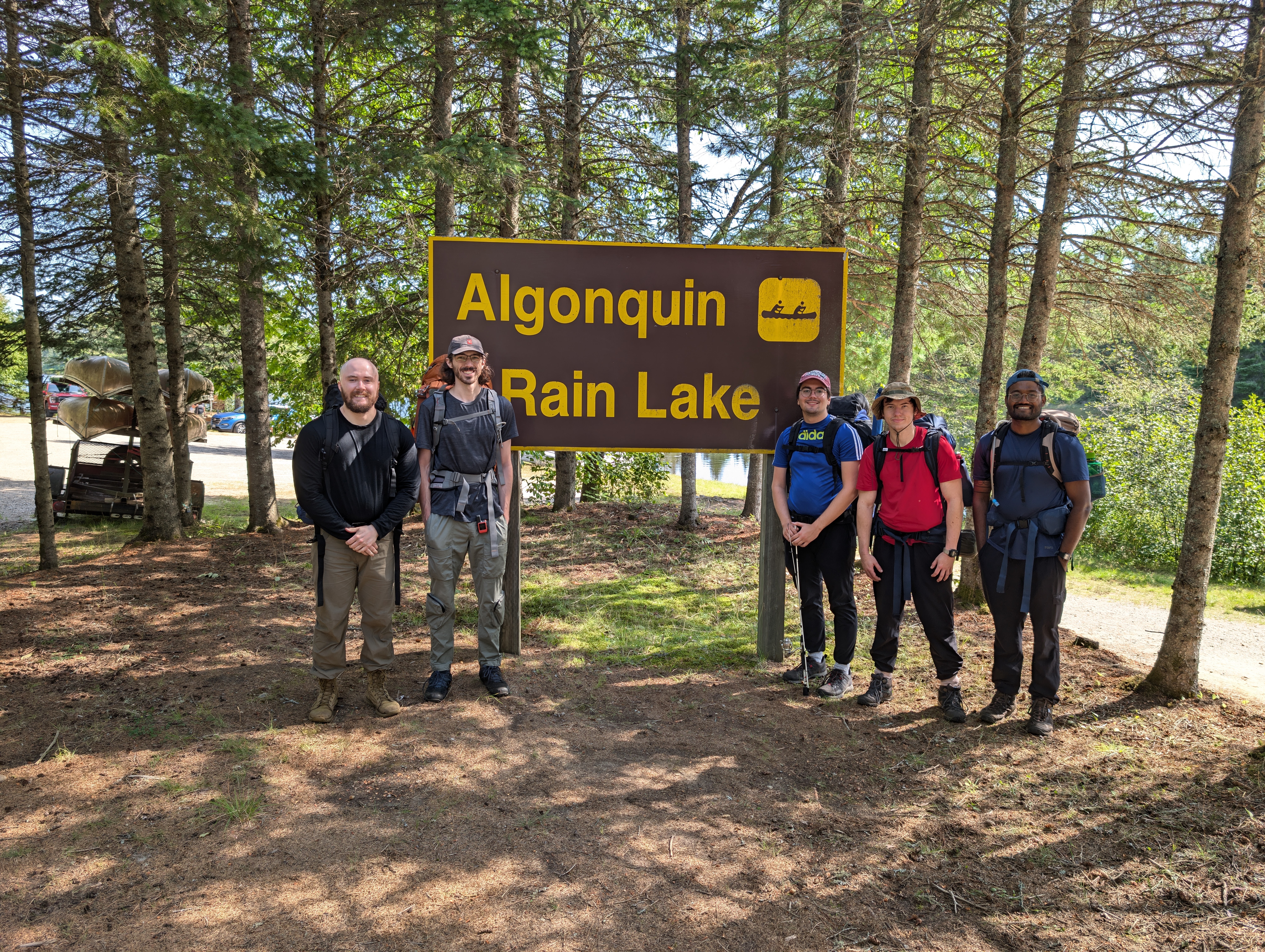 Group of 5 guys in front of a sign that says Algonquin Rain Lake at the end of the hike